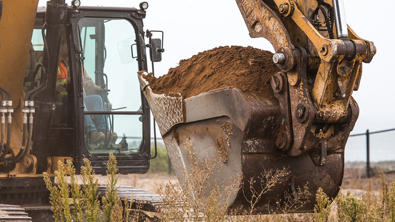 Excavator with dirt in bucket.