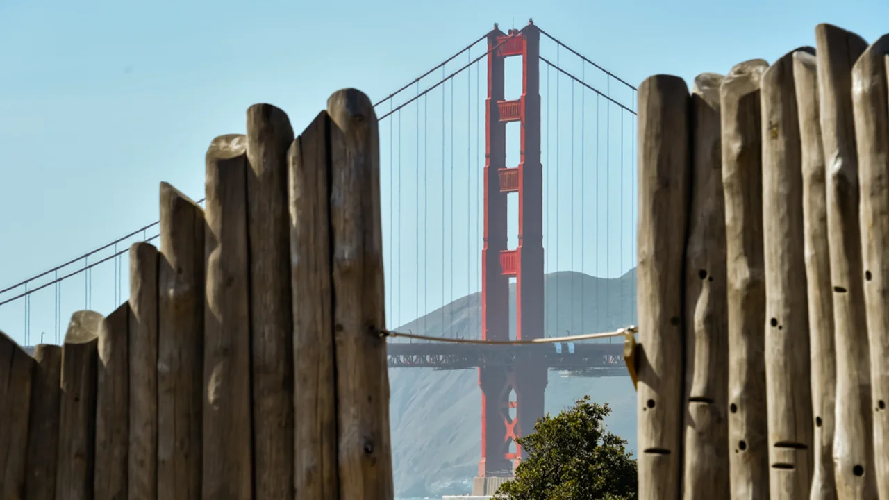 The Golden Gate Bridge is seen through the climbing wall of the Presidio Tunnel Tops Outpost playground.