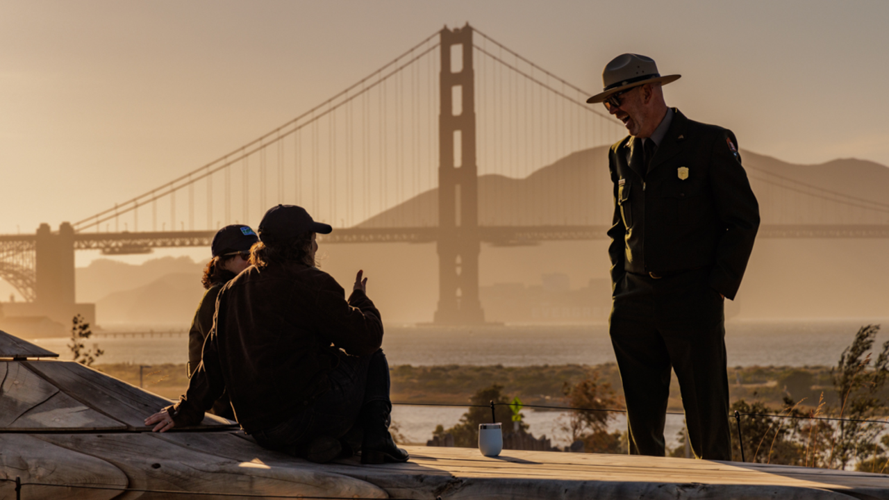 NPS ranger enjoying a conversation at the Presidio Tunnel Tops with the Golden Gate Bridge backdrop.