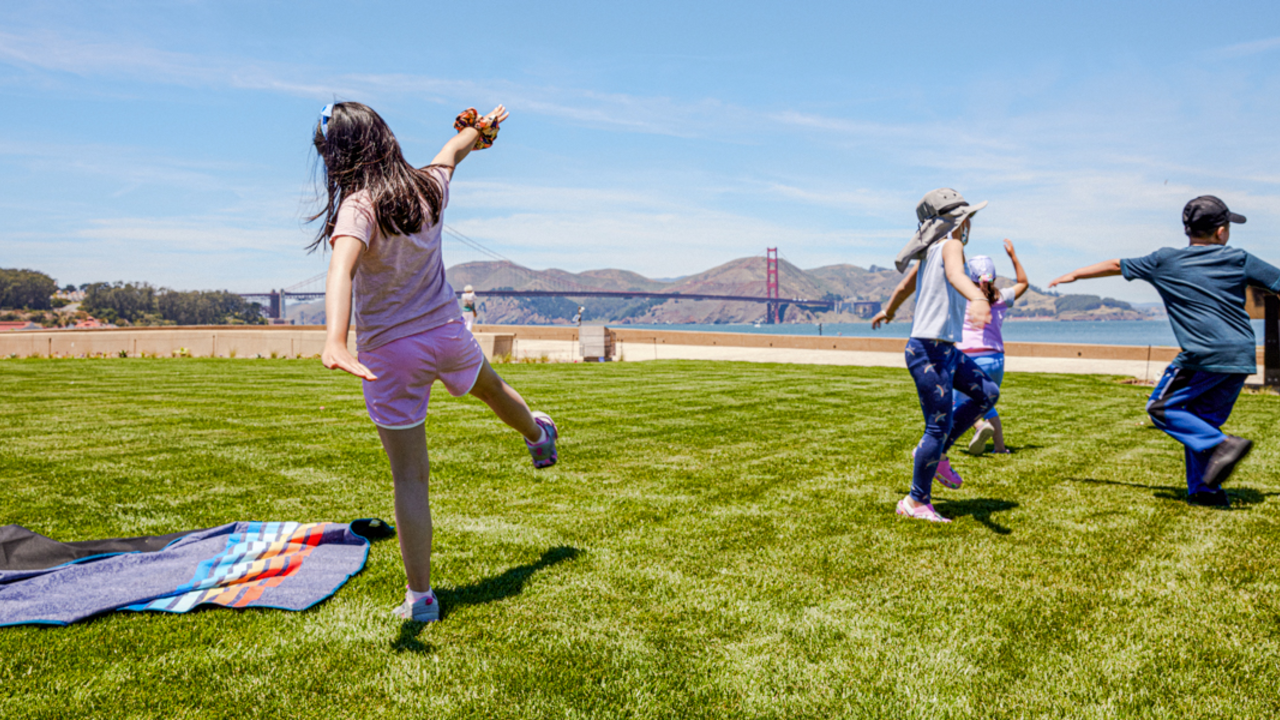 Kids stretch and play, running around the Presidio Tunnel Tops lawn.