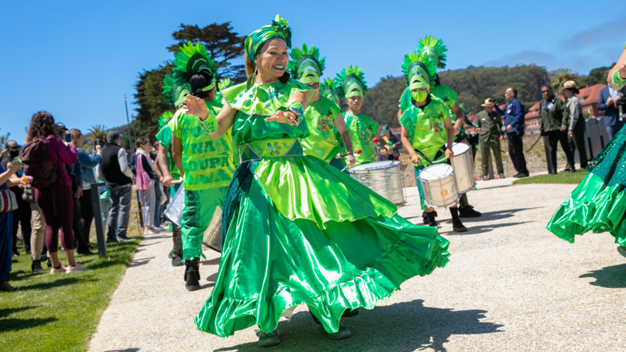 Fogo Na Roupa dancers perform at the Presidio Tunnel Tops on opening day. The dancers of Fogo Na Roupa celebrate in bright green regalia at the newly opened Presidio Tunnel Tops.