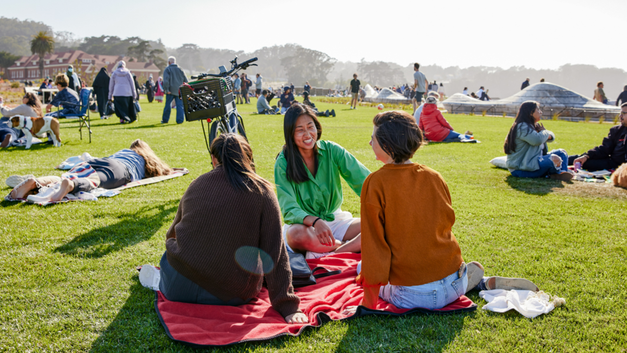 People sit and lay on blankets all about the Golden Gate Meadow at Presidio Tunnel Tops.