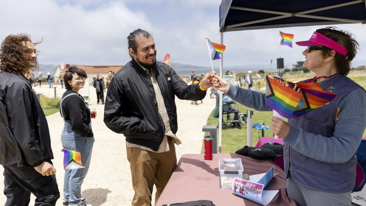 Staff hand out mini rainbow flags to park visitors.