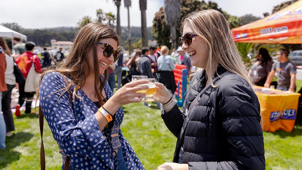 Friends cheers with souvenir beer tasting glasses at Parks4All: Brewfest, a beer festival and fundraiser, on Saturday, July 29th, 2023 in the Presidio of San Francisco.