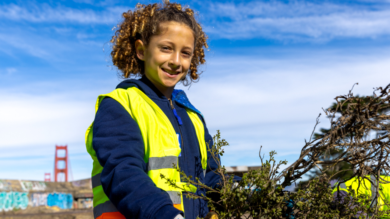 MLK Jr. Weekend of Service in The Presidio A young volunteer smiles while carrying debris during MLK day of service at the presidio in san francisco