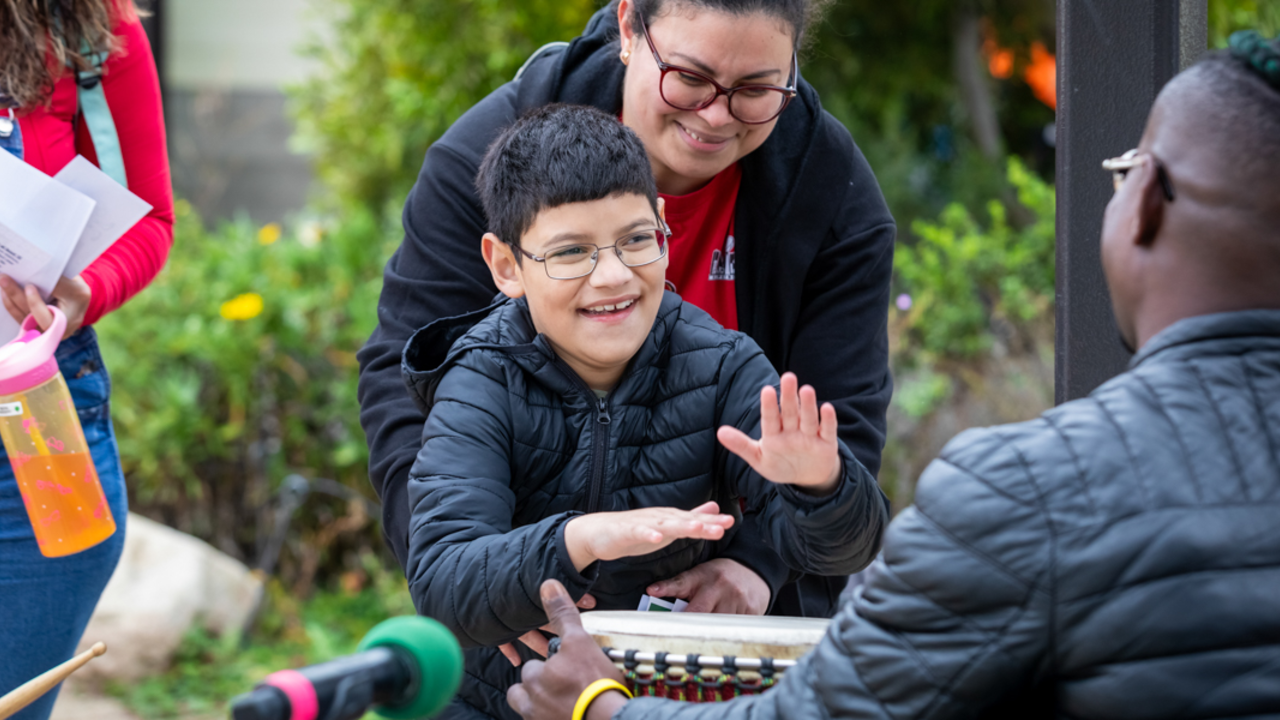 Access to Adventure Day A child smiles while playing a drum alongside parent and community at Access to Adventure day in the Presidio of San Francisco
