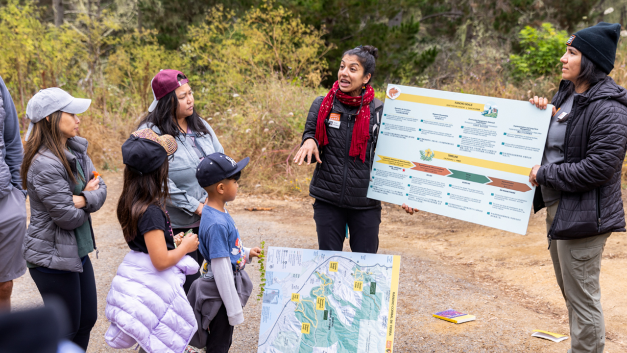 Parks Conservancy staff connecting communities to their local parks. Parks Conservancy Community Engagement staff holding a sign, informing the local community at Rancho Corral de Tierra.