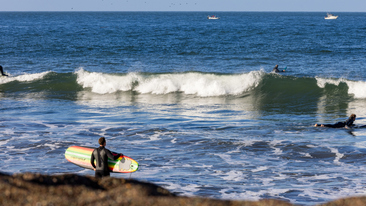 Surfers catch waves on a sunny day at Rodeo Beach in the Marin Headlands