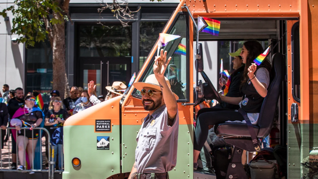 NPS park ranger marches alongside the Roving Ranger mobile trailhead at the 2022 SF Pride parade.