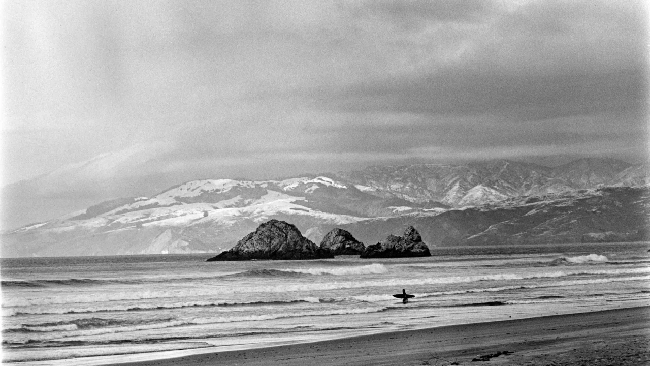 Surfer at Ocean Beach with snowy Marin Headlands in background