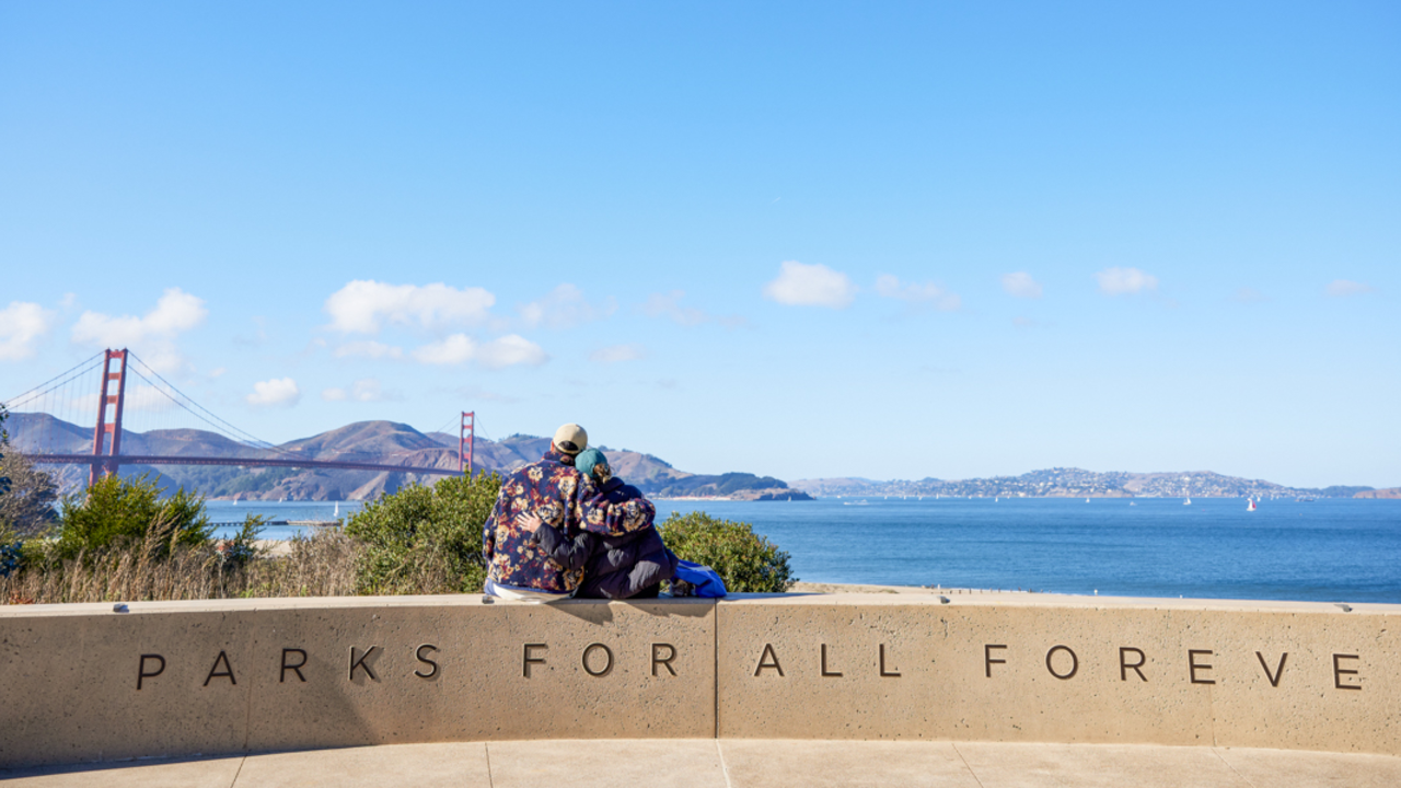 Golden Gate view from Battery Bluff in the Presidio A embracing couple sits and looks out at the golden gate bridge, marin headlands, and san francisco bay