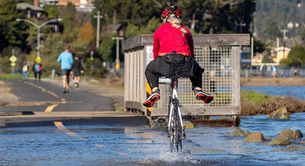 A bicyclist rides through water along a pedestrian path in Marin County.