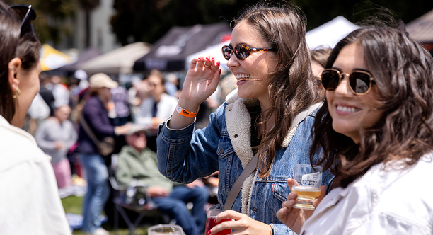 Two attendees smile with souvenir tasting glasses at Parks4All: Brewfest, a beer festival and fundraiser, on Saturday, July 29th, 2023 in the Presidio of San Francisco.