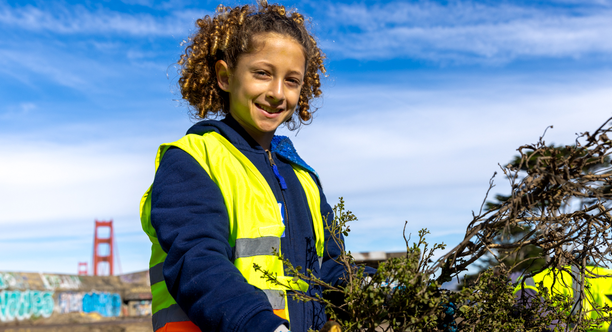 A young volunteer smiles while carrying debris during MLK day of service at the presidio in san francisco