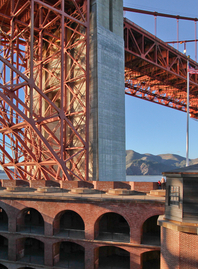 View of the Golden Gate Bridge and the top of Fort Point National Historic Site set against a blue sky
