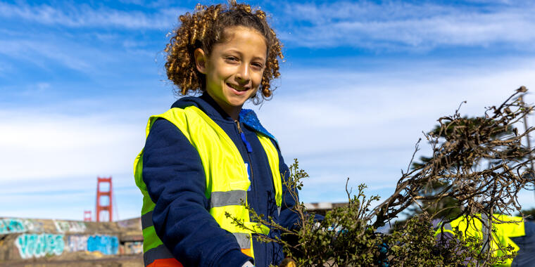 A young volunteer smiles while carrying debris during MLK day of service at the presidio in san francisco