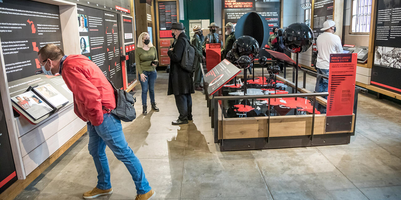 Visitors examine information about incarceration on red and black panels around the new 'Big Lockup' exhibit.