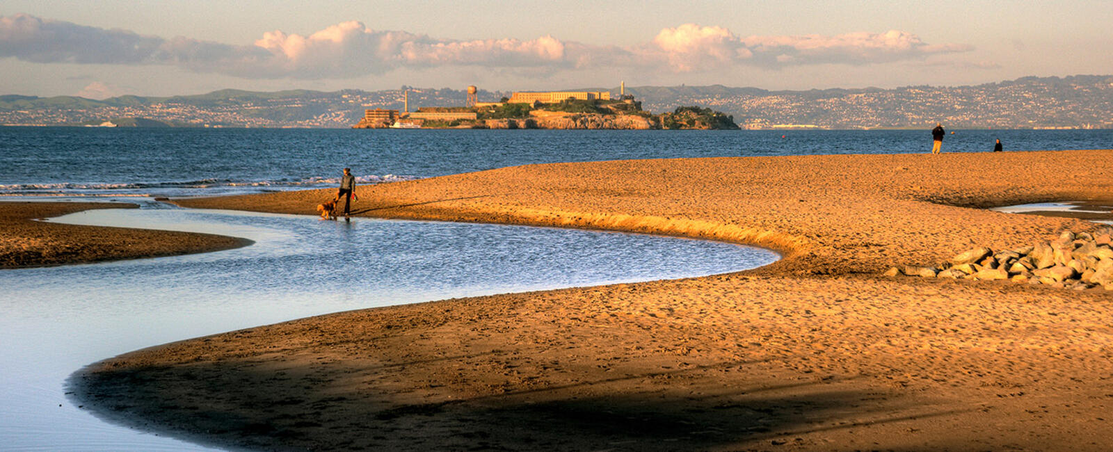 People enjoy East Beach at Crissy Field, with Alcatraz Island in the distance.