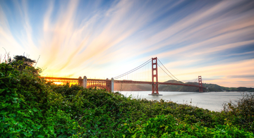 The Golden Gate Bridge seen with orange and yellow sunset in the background.
