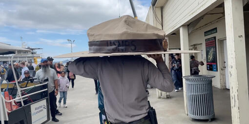 Two NPS staff members carry the Big Hat to the Alcatraz ferry. 