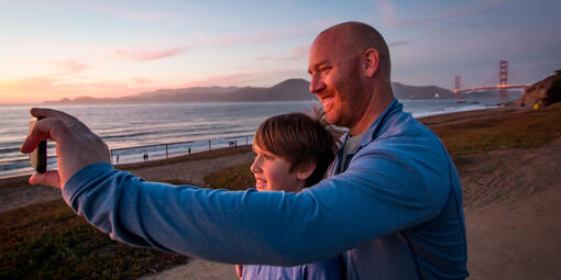 Father and son pose for a selfie at Baker Beach in San Francisco.
