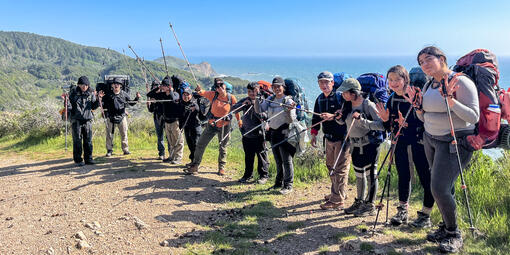 IYEL youth program participants pose before the scenic backdrop of trees and ocean on a backpacking trip in Marin