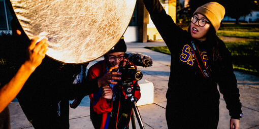 Crissy Field Center youth program participants working a photoshoot, holding a camera and light reflector.