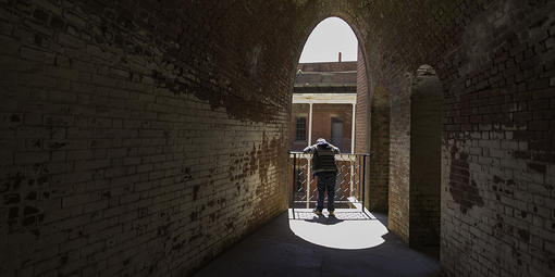 A dark hall leads to a person looking down through a sunny archway on one of Fort Points upper levels