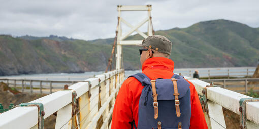 Person in red jacket with a blue backpack talking down the pathway at Point Bonita Lighthouse.