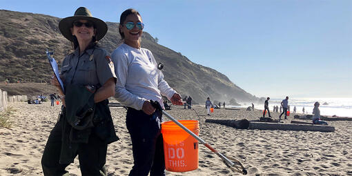 Two volunteers posing with supplies while cleaning up Muir Beach