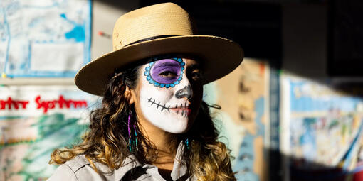 A portrait of an  NPS ranger with candy skull face paint on for Dia de los Muertos.