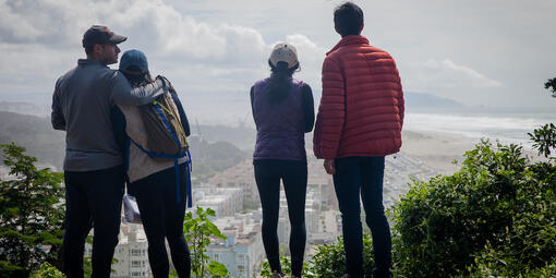 Four people stand on edge of Sutro Heights Parks looking out towards Ocean Beach and Golden Gate Park