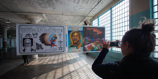 Woman takes photo of Future IDs display in the New Industries Building on Alcatraz.