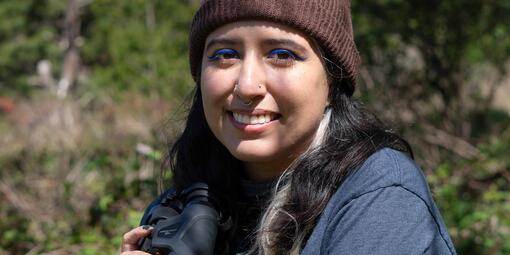 Portrait of birder Daniela Sánchez with binoculars on a birding trip.