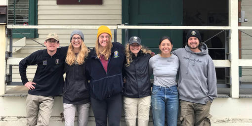 A group of interns pose together outside of a building while smiling at the camera