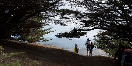 People hiking down a winding path at Rancho Corral de Tierra.