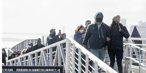 a group of masked visitors disembark from a ship onto Alcatraz