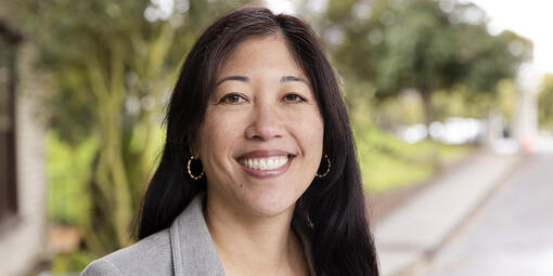 Michele Gee stands in front of a green background in the parks.