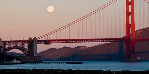 The moon rises above the bridge