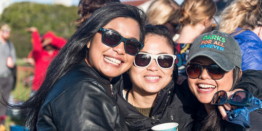 Three woman wearing sunglasses smile for photo.