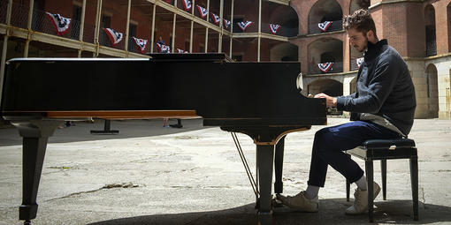 Pianist plays piano surrounded by the red-bricked Fort Point.