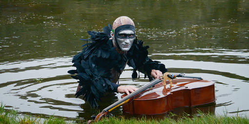 Musician Andy Meyerson wears an elaborate costume with a cello floating in Sutro Baths.