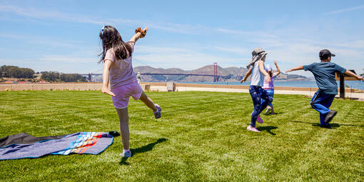 Kids stretch and play, running around the Presidio Tunnel Tops lawn.