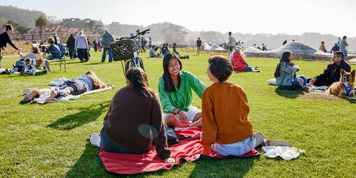 People sit and lay on blankets all about the Golden Gate Meadow at Presidio Tunnel Tops.