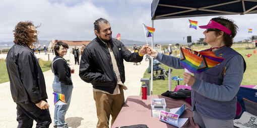 Staff hand out mini rainbow flags to park visitors.