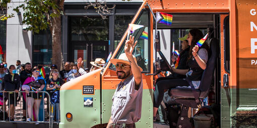NPS park ranger marches alongside the Roving Ranger mobile trailhead at the 2022 SF Pride parade.