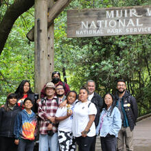 A group from the American Indian Cultural District stands together at the entrance of Muir Woods National Monument