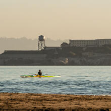 A Kayak paddles over the Golden Gate waters, viewed before Alcatraz Island from Crissy Field East Beach.