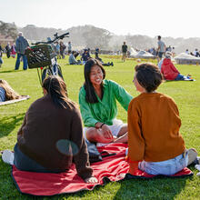 People sit and lay on blankets all about the Golden Gate Meadow at Presidio Tunnel Tops.