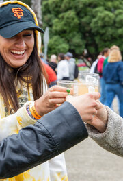 Three smiling and laughing women raise their glasses at the Parks4All: Brewfest in the Presidio